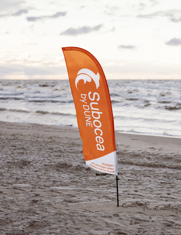 Drapeau publicitaire sur la plage avec le logo de Subocea by Dune